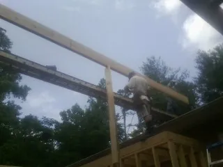 Carpenter setting a ridge beam over a new addition frame — Ice Dam Removal by Roofing Brothers in Drexel